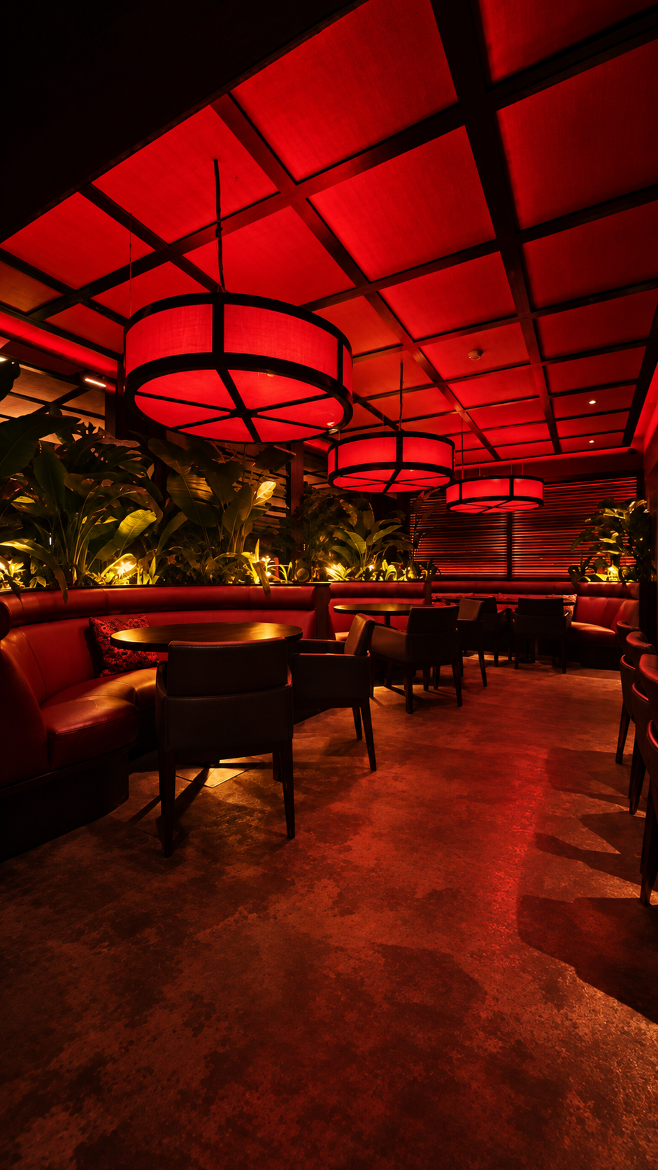 Red-lit dining room at Zen with large glowing circular lanterns, banquette seating and tropical planting.